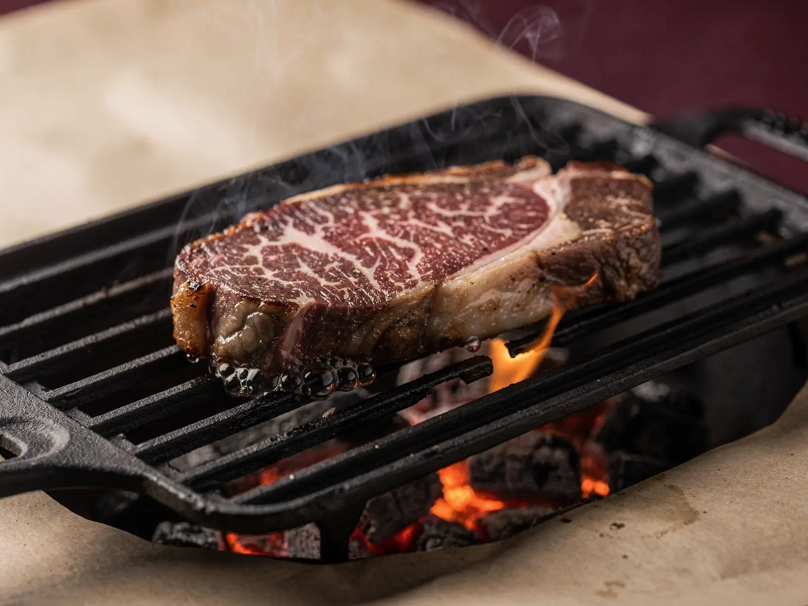 Corte de wagyu veteado sobre una parrilla de hierro, con las brasas encendidas debajo (imagen generada con IA)