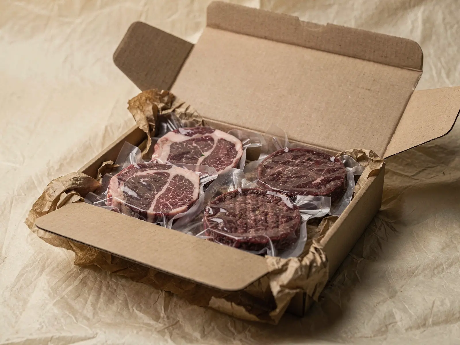 Filetes y hamburguesas de wagyu envasados al vacío dentro de una caja de cartón abierta (imagen generada con IA)